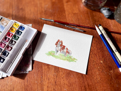 Watercolor painting of a dog on paper with art supplies on a wooden surface.