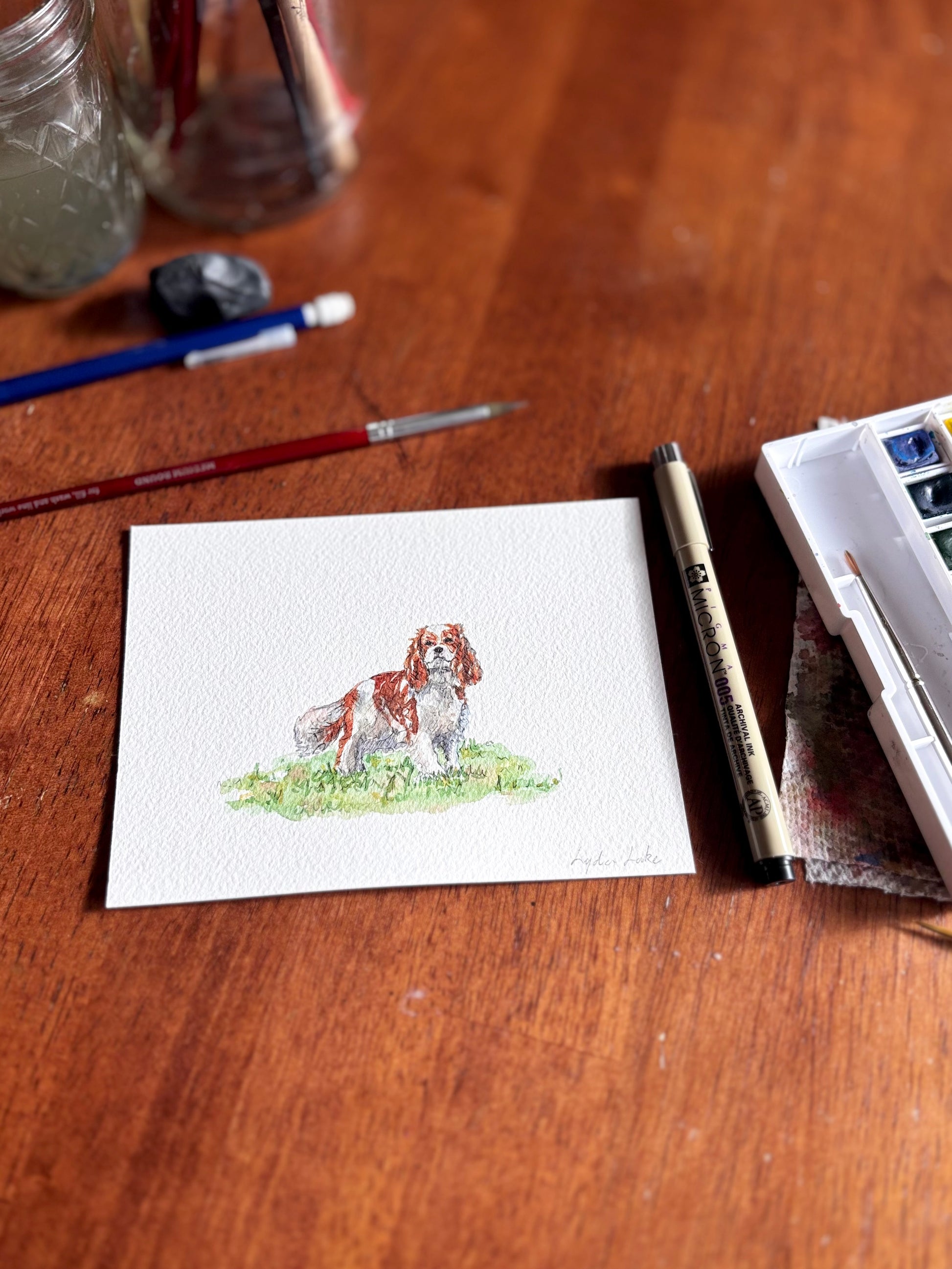 Watercolor painting of a dog on a wooden surface with art supplies.