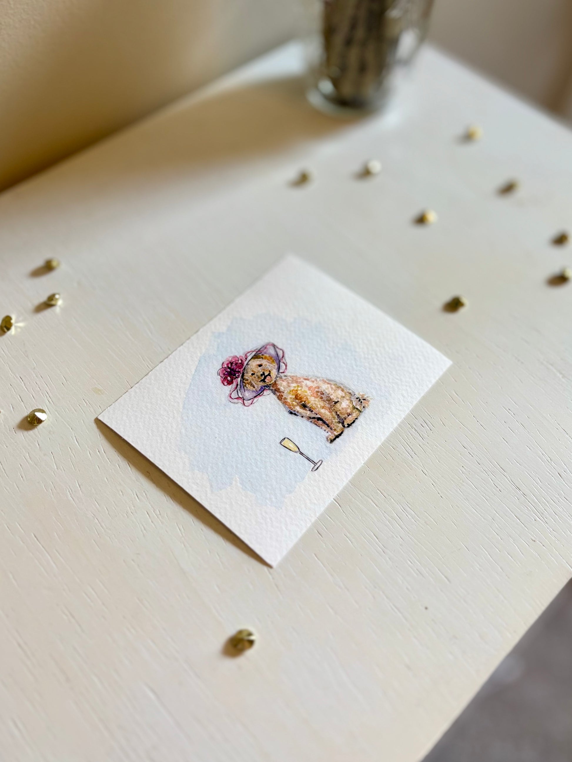 Small watercolor painting of a Golden Doodle with a hat on a white surface.