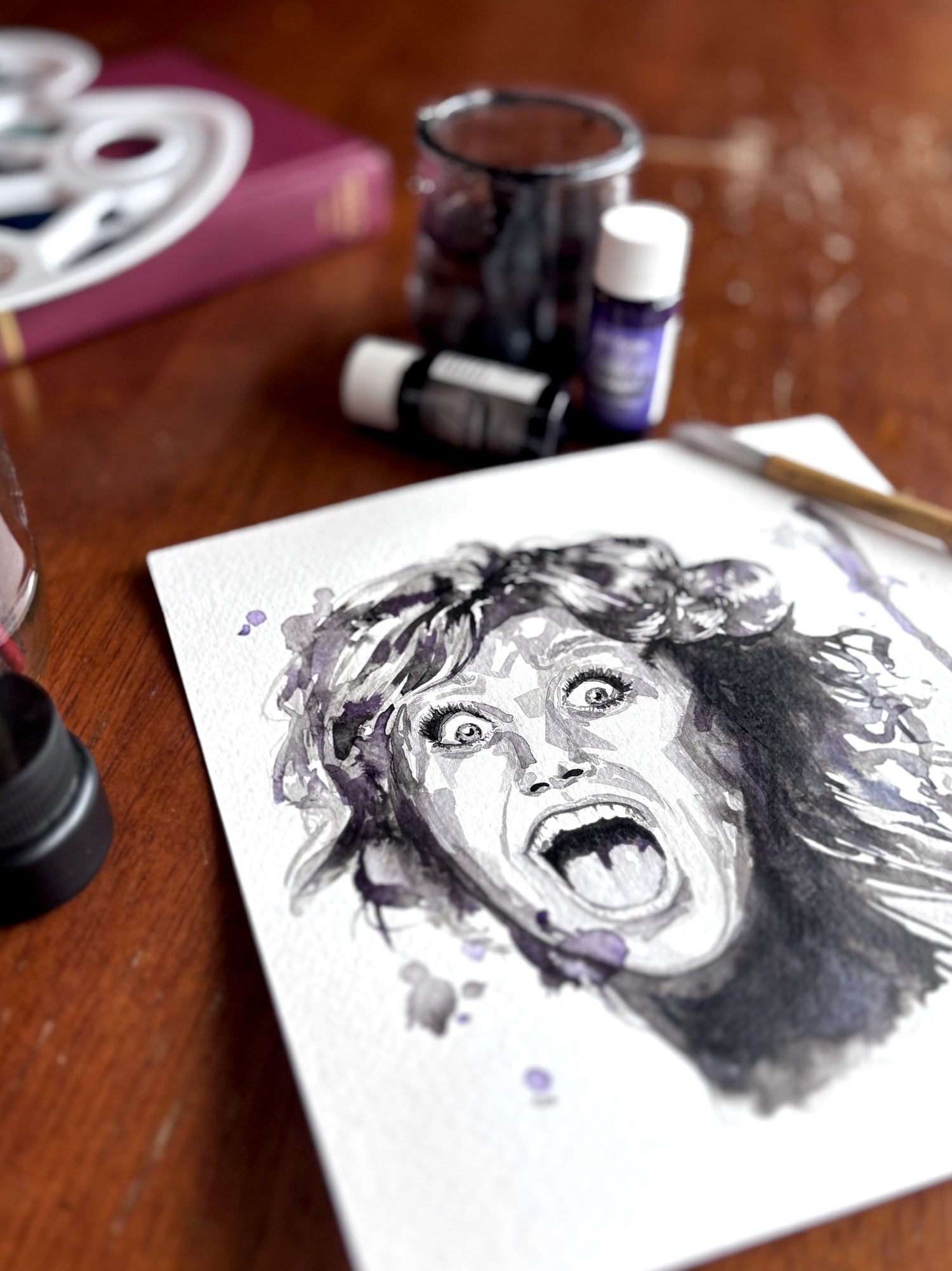 Artistic depiction of a person on a piece of paper, surrounded by art supplies on a wooden surface.